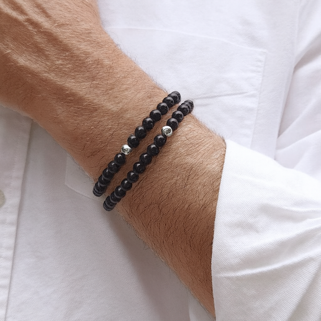Black beaded bracelet on a wrist with a white shirt background