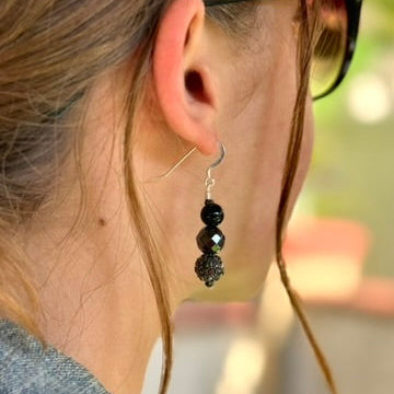 Close-up of an ear wearing a black beaded earring with sunglasses on.