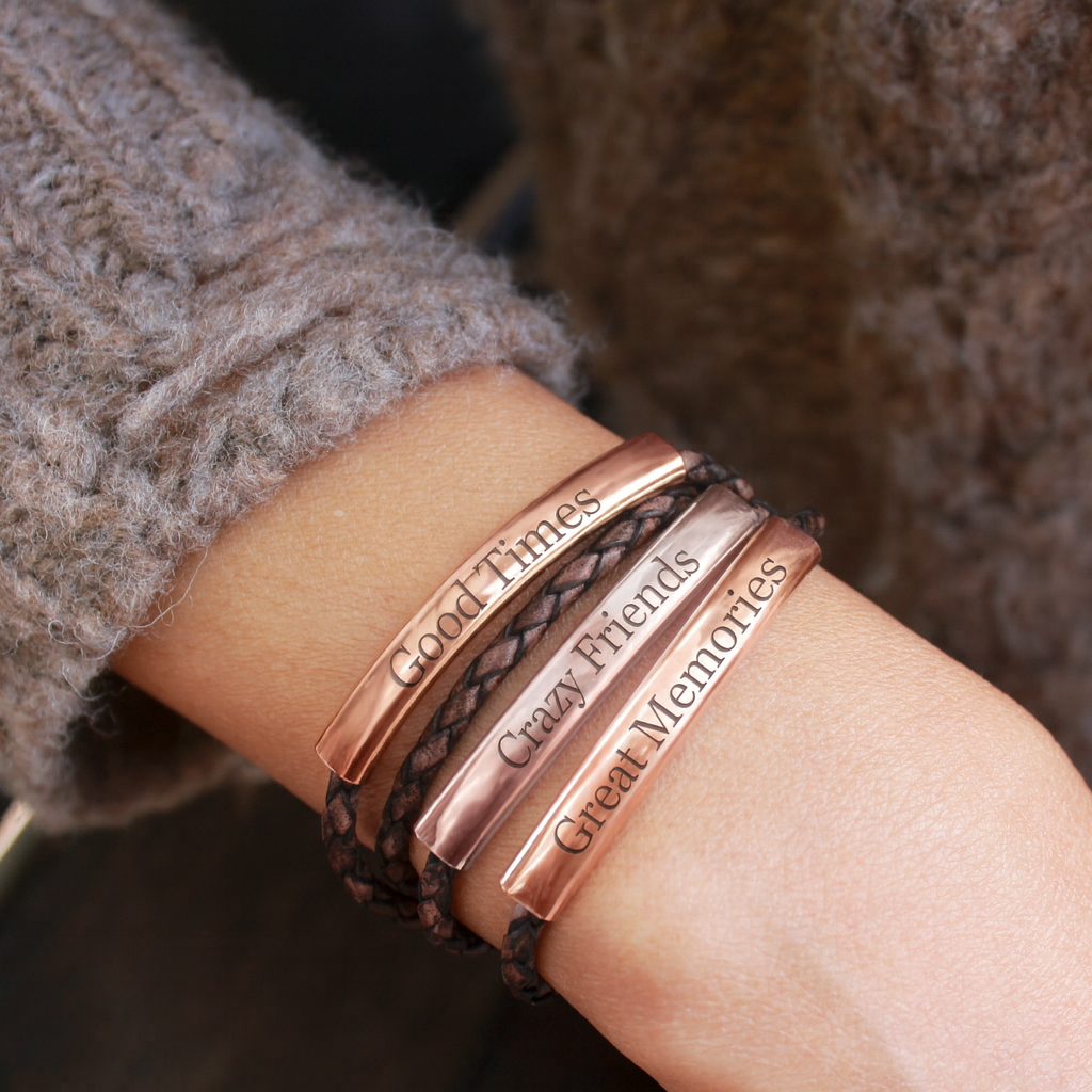 Close-up of a wrist wearing multiple copper bracelets with engravings.