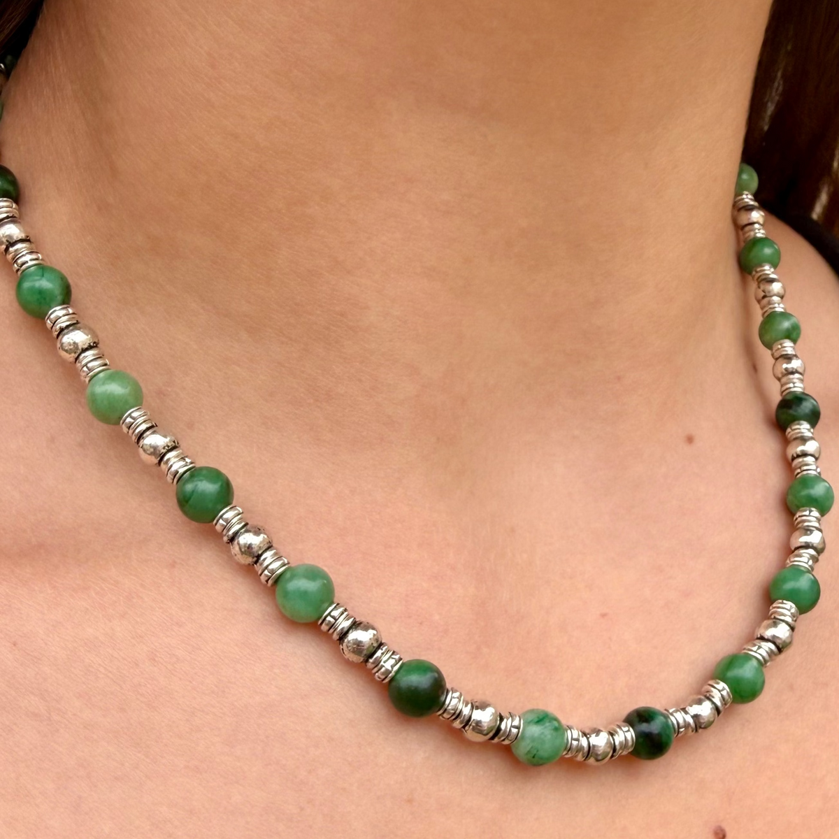 Necklace with green beads and silver accents on a person's neck