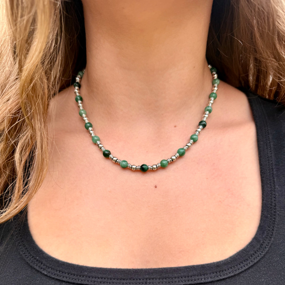Green beaded necklace worn by a person with a blurred background