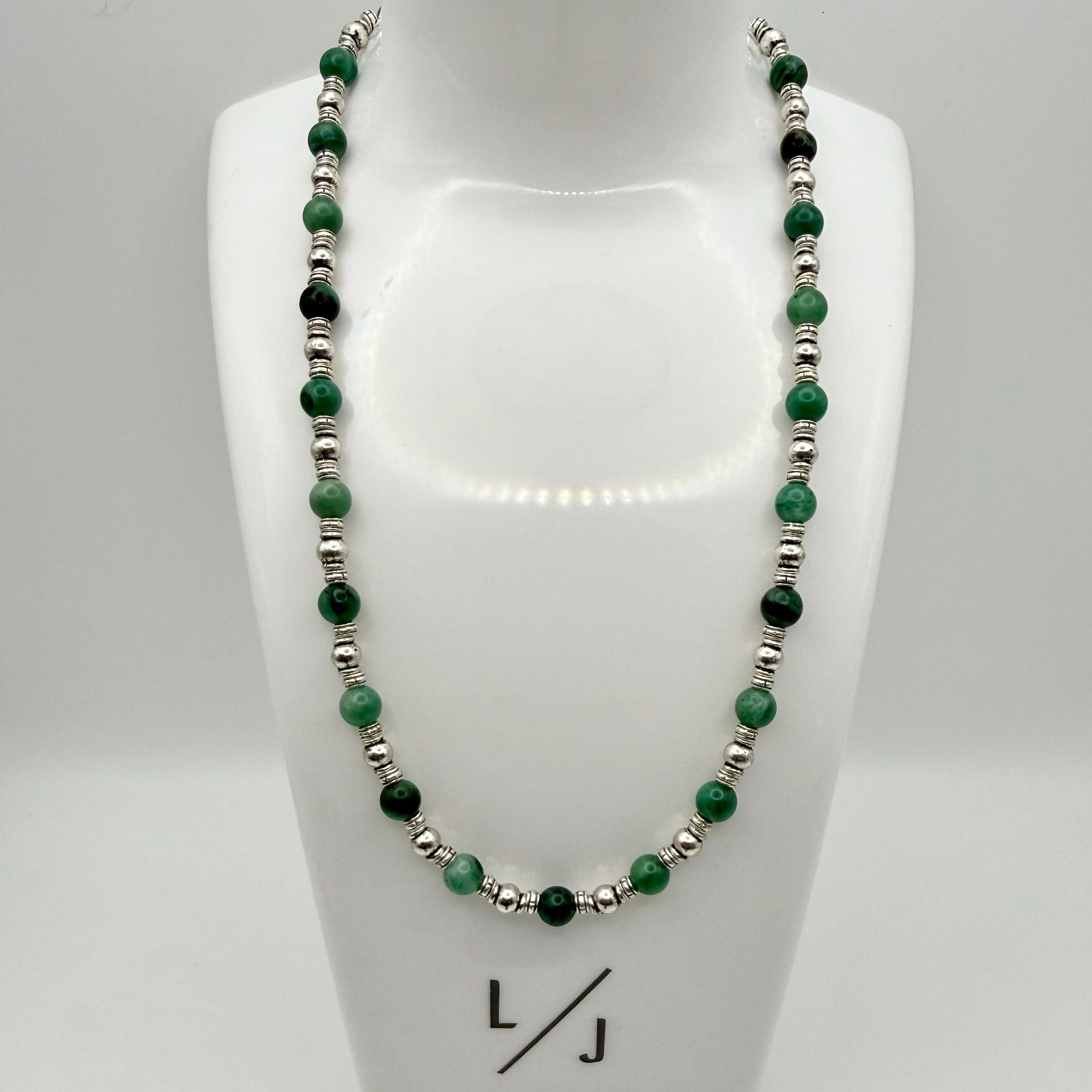 Necklace with green beads and silver accents on a person's neck