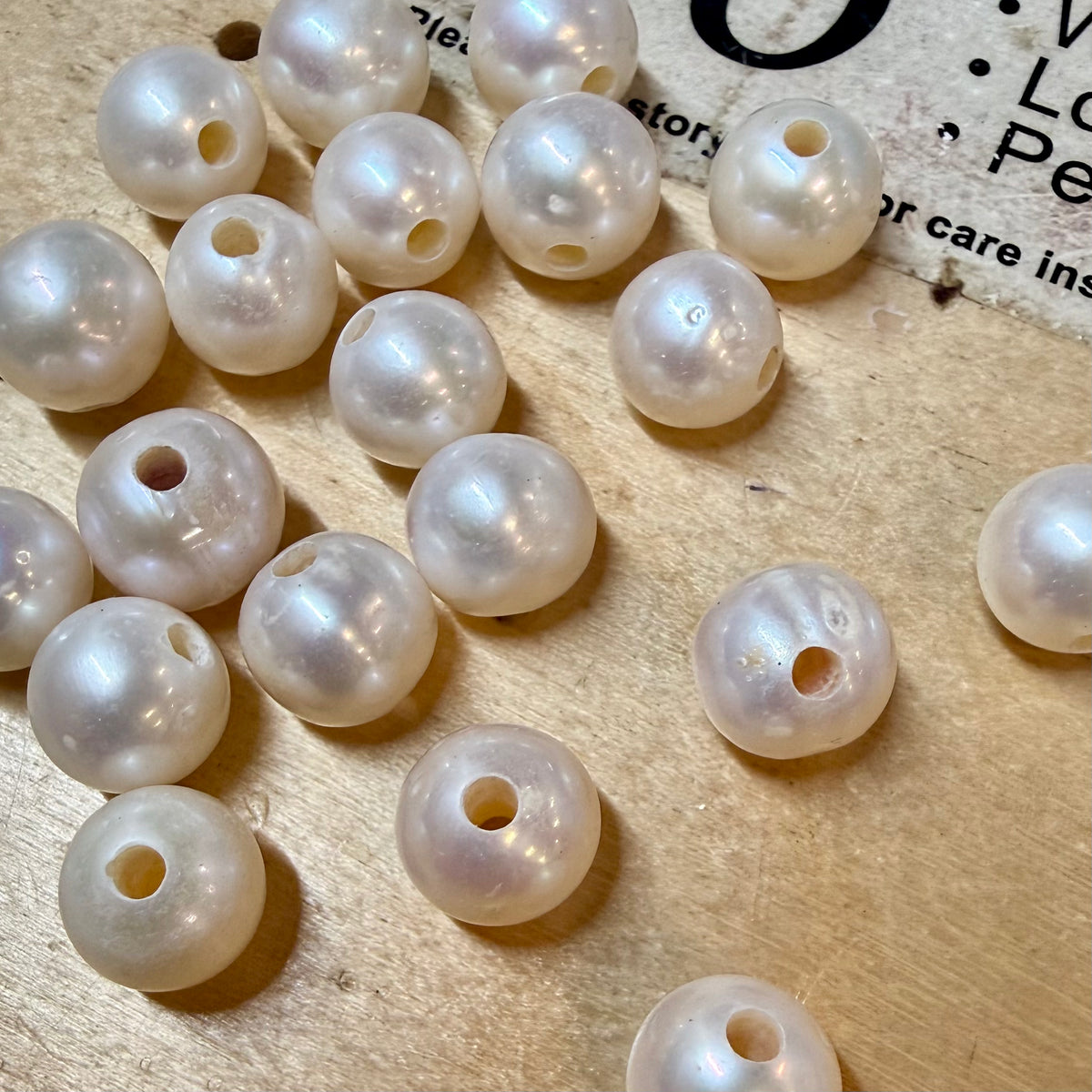 White pearls on a wooden surface with text in the background