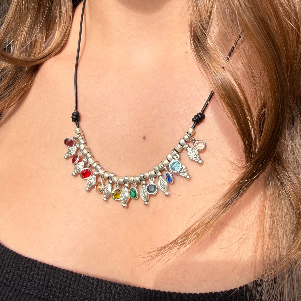 Necklace with colorful beads and silver accents worn by a person with long hair.