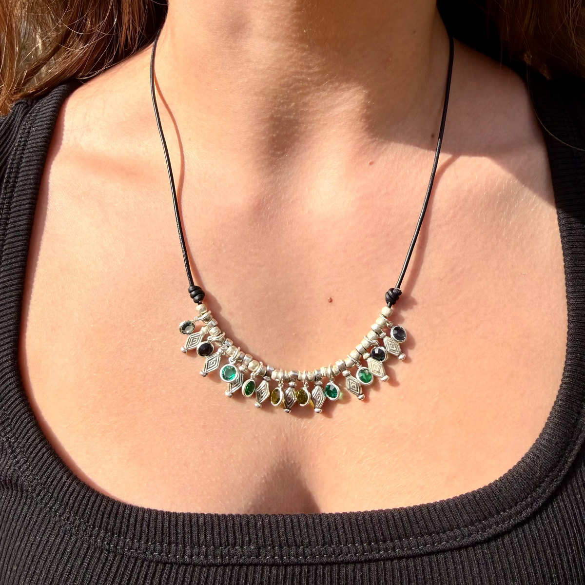 Necklace with colorful beads worn by a person against a black top.