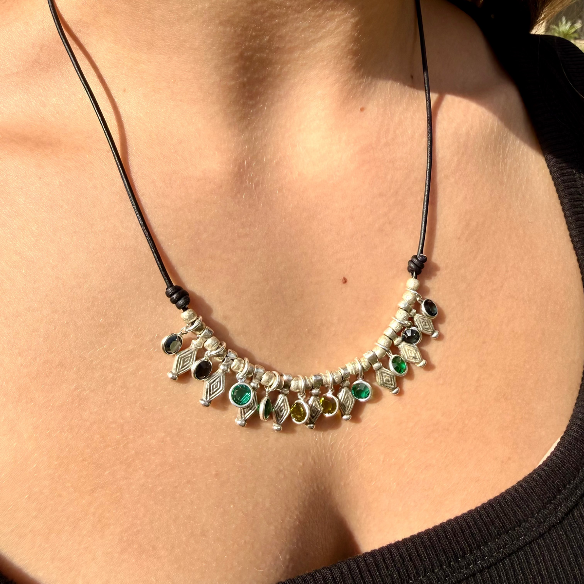 Necklace with decorative pendants on a person wearing a black top.
