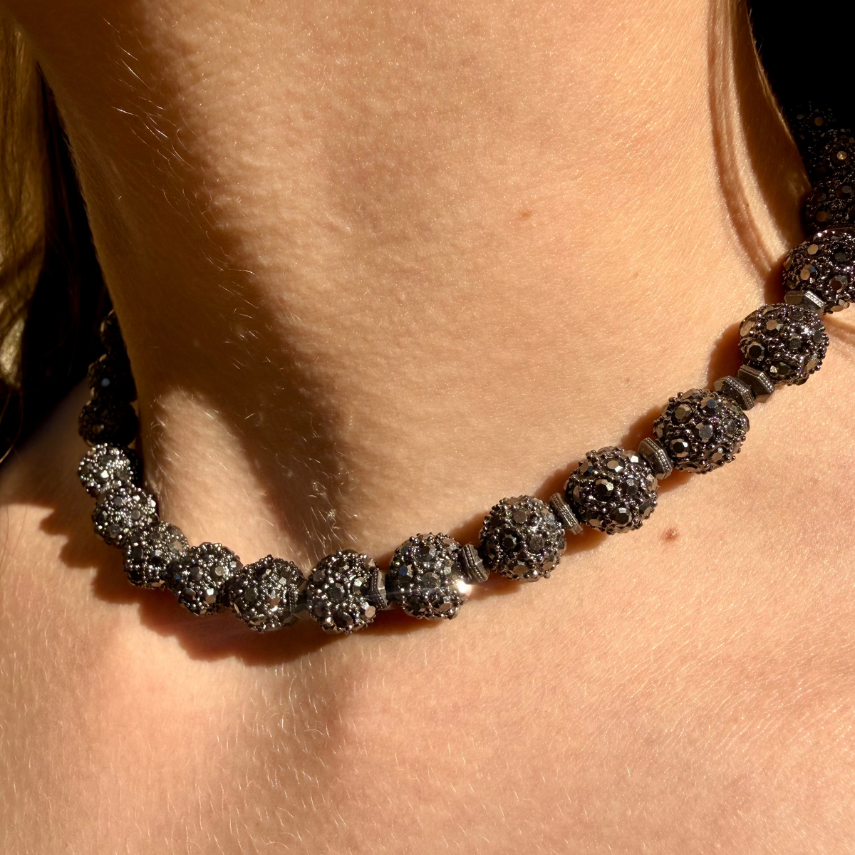 Close-up of a necklace with dark beads on a person's neck