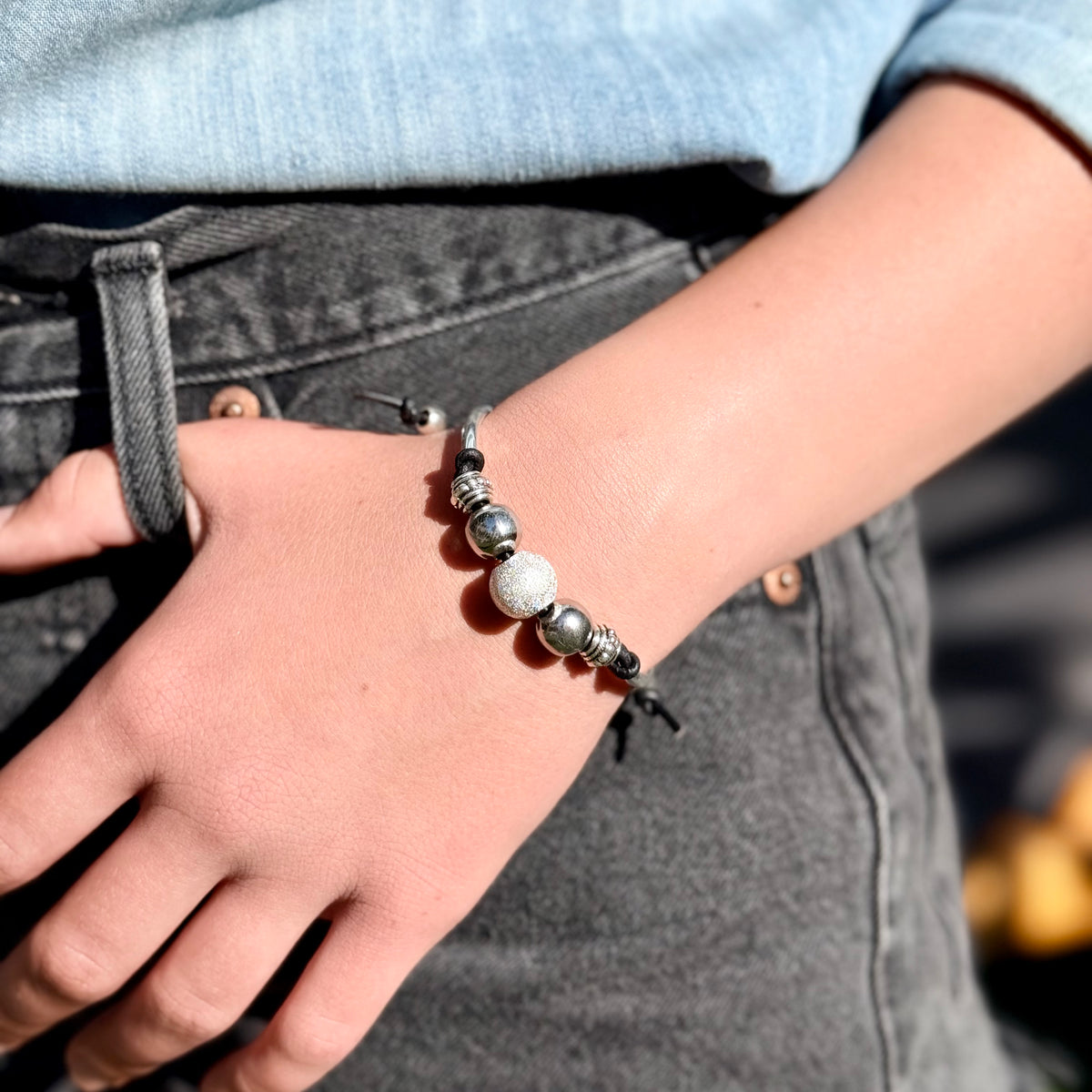 Close-up of a person's wrist wearing a beaded bracelet with a blurred background