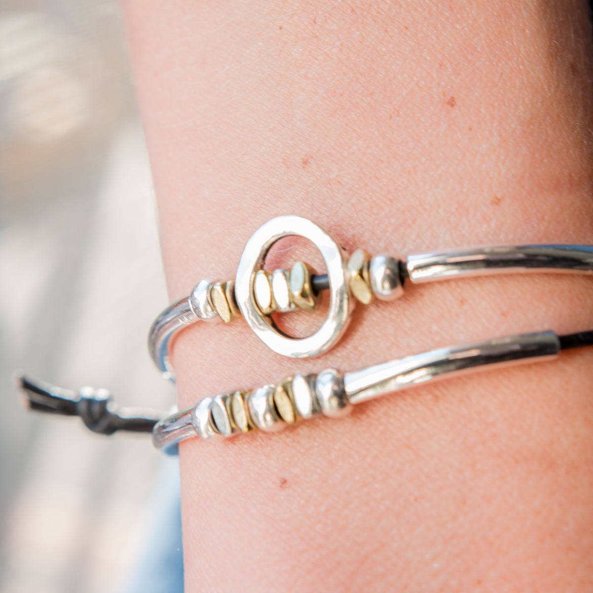 Silver and gold bracelet on a wrist with a blurred background