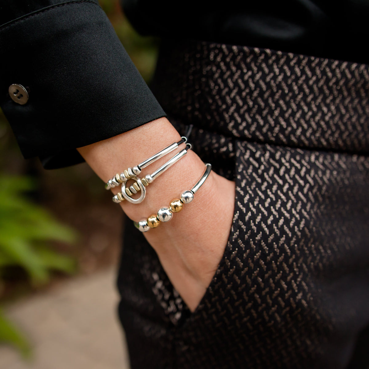 Close-up of a person wearing multiple bracelets on a blurred outdoor background