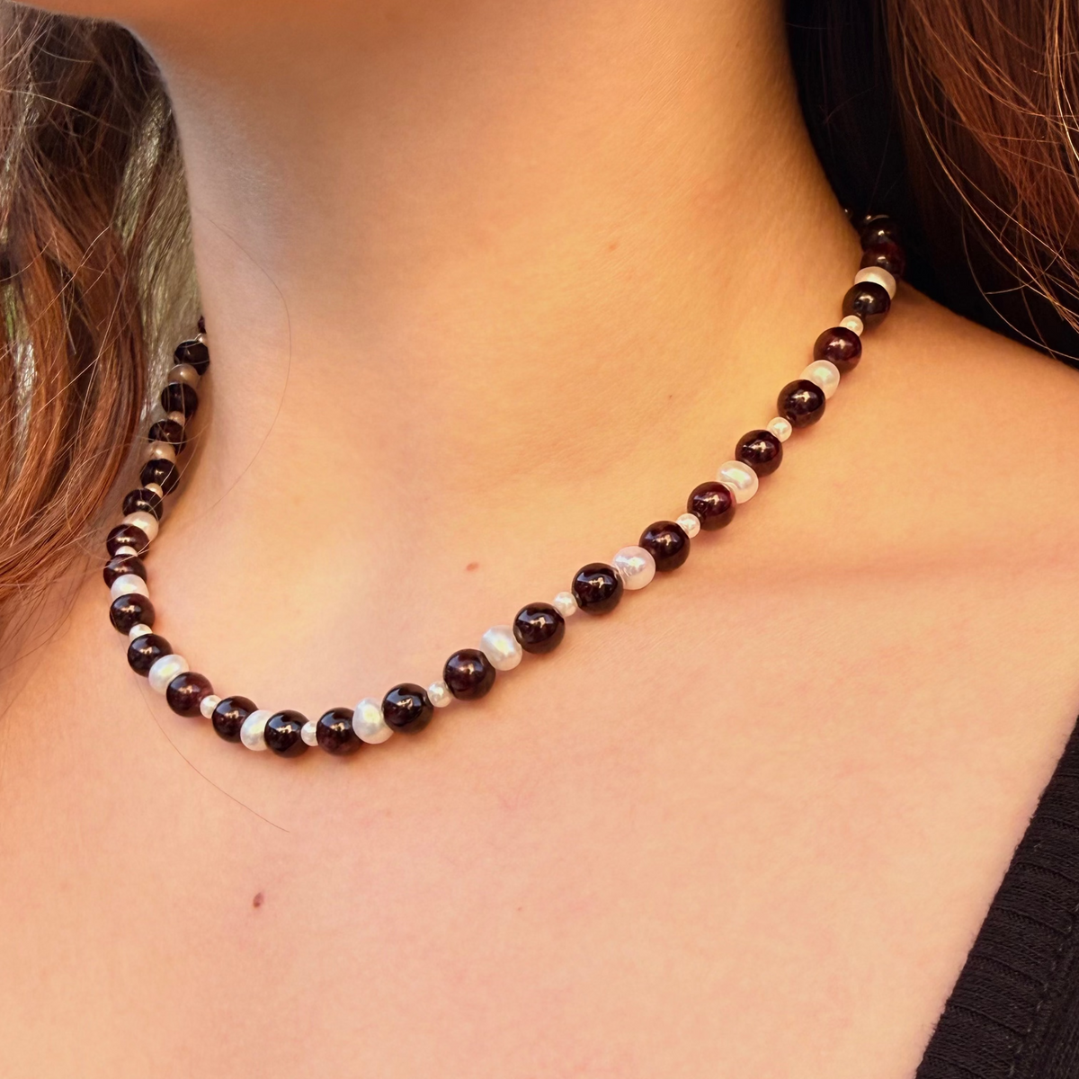 Close-up of a person wearing a beaded necklace with a blurred background