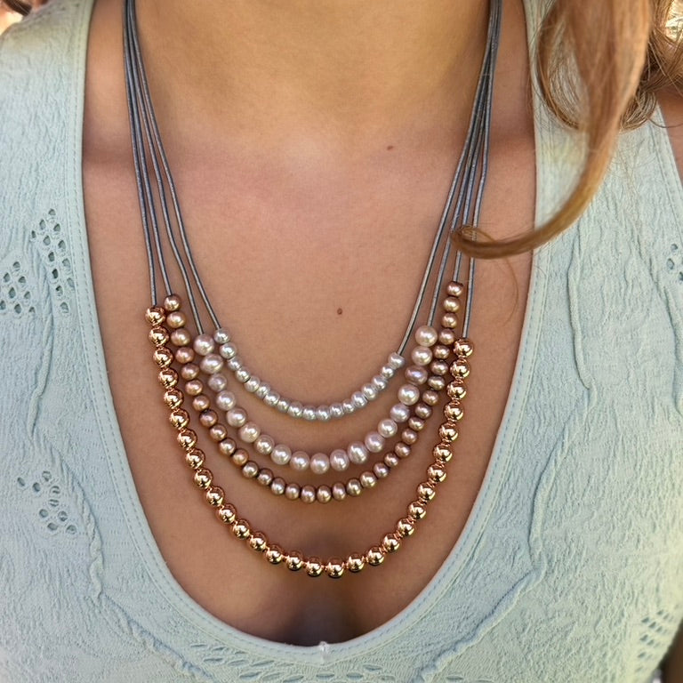 Necklace with pearls and gold beads worn by a person in a light blue top.