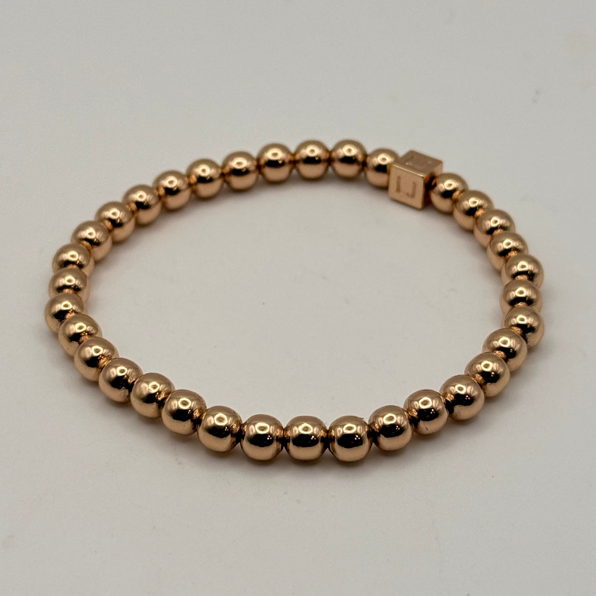 Rose gold beaded bracelet on a light gray background