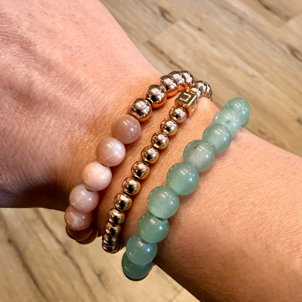 Two beaded bracelets on a wrist with a wooden surface background