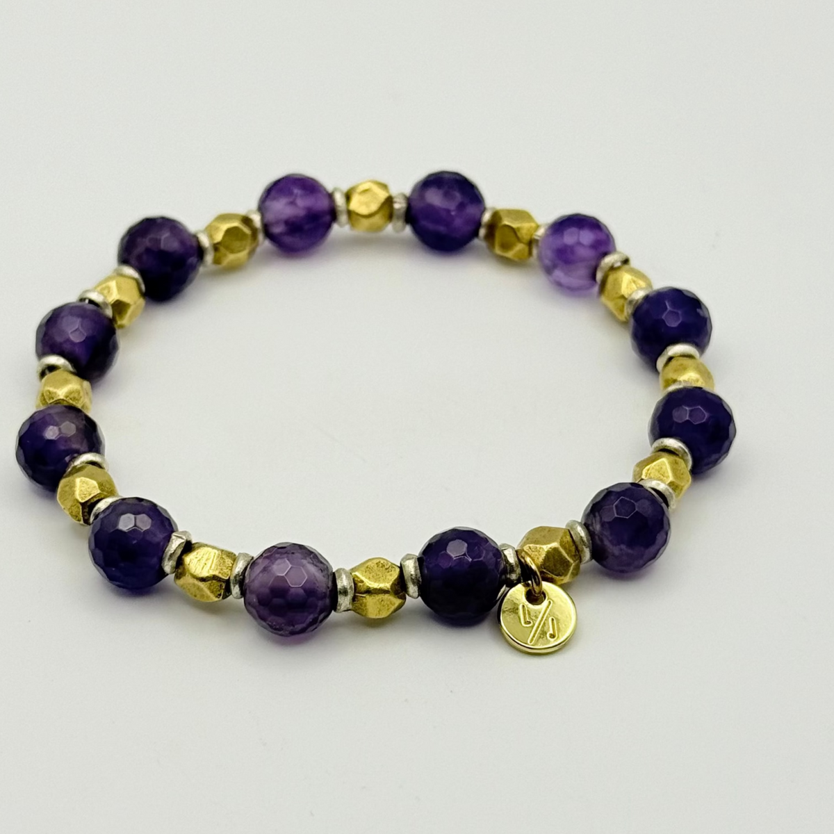 Bracelet with purple and gold beads on a light gray background