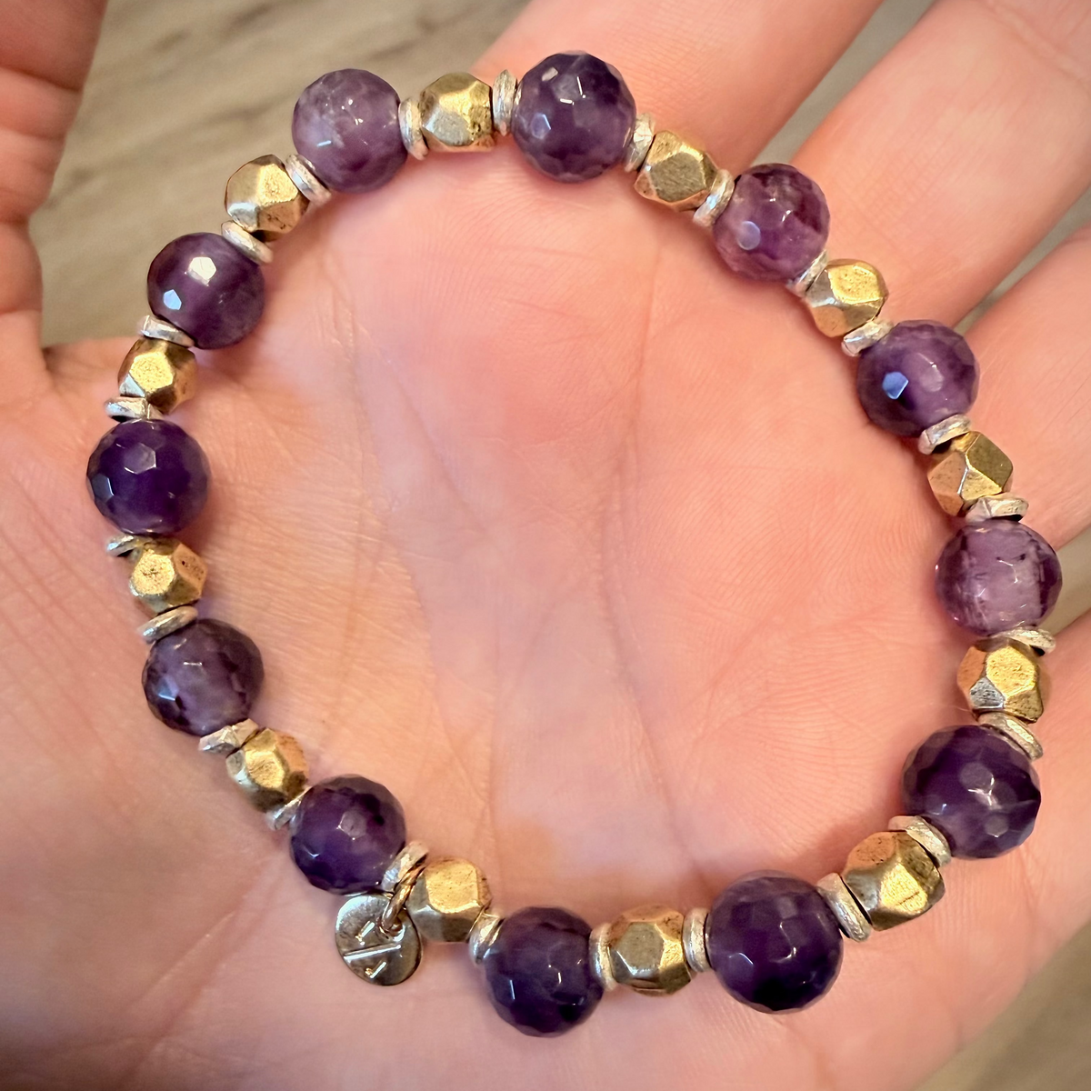 Purple beaded bracelet with gold accents on a hand