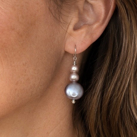 Close-up of an ear wearing a pearl earring with a neutral background