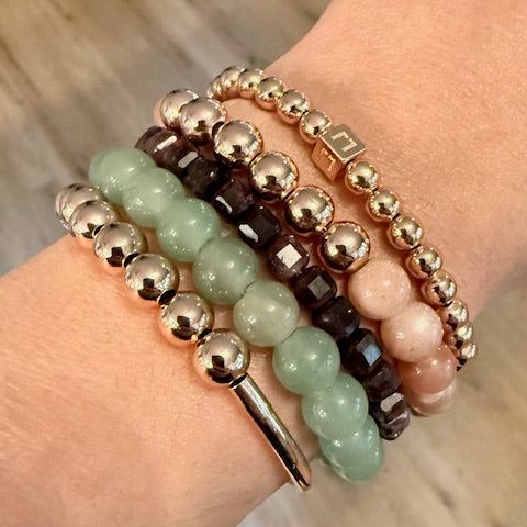 Stack of beaded bracelets on a wrist with a blurred wooden surface background