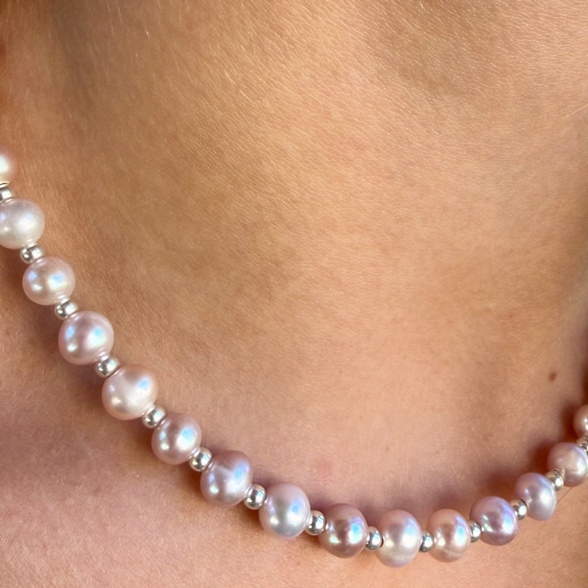 Close up detail photo of Roselle pink pearl necklace worn at the neckline with delicate silver-plated bead accents