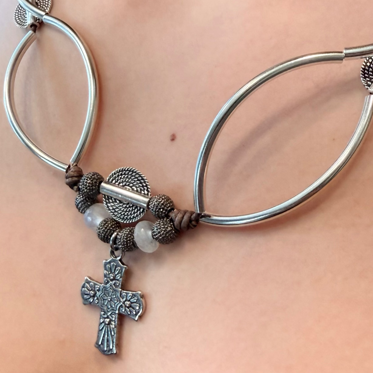 Selene convertible jewelry: a brown leather cross necklace with moonstone beads that wraps into a layered bracelet.
