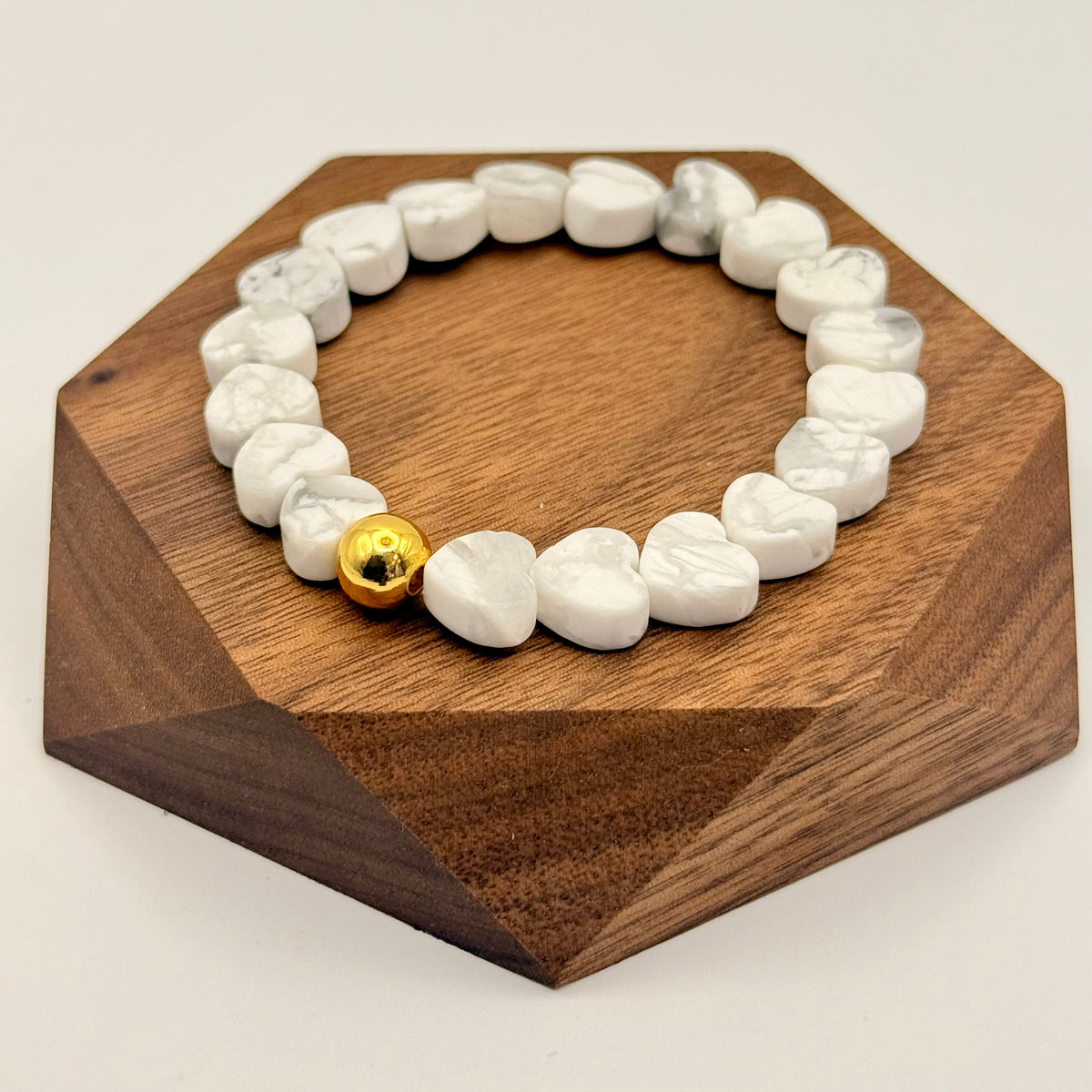 Howlite Heart Stretch-to-Fit Bracelet with one gold accent bead laying on a wood block for studio photo