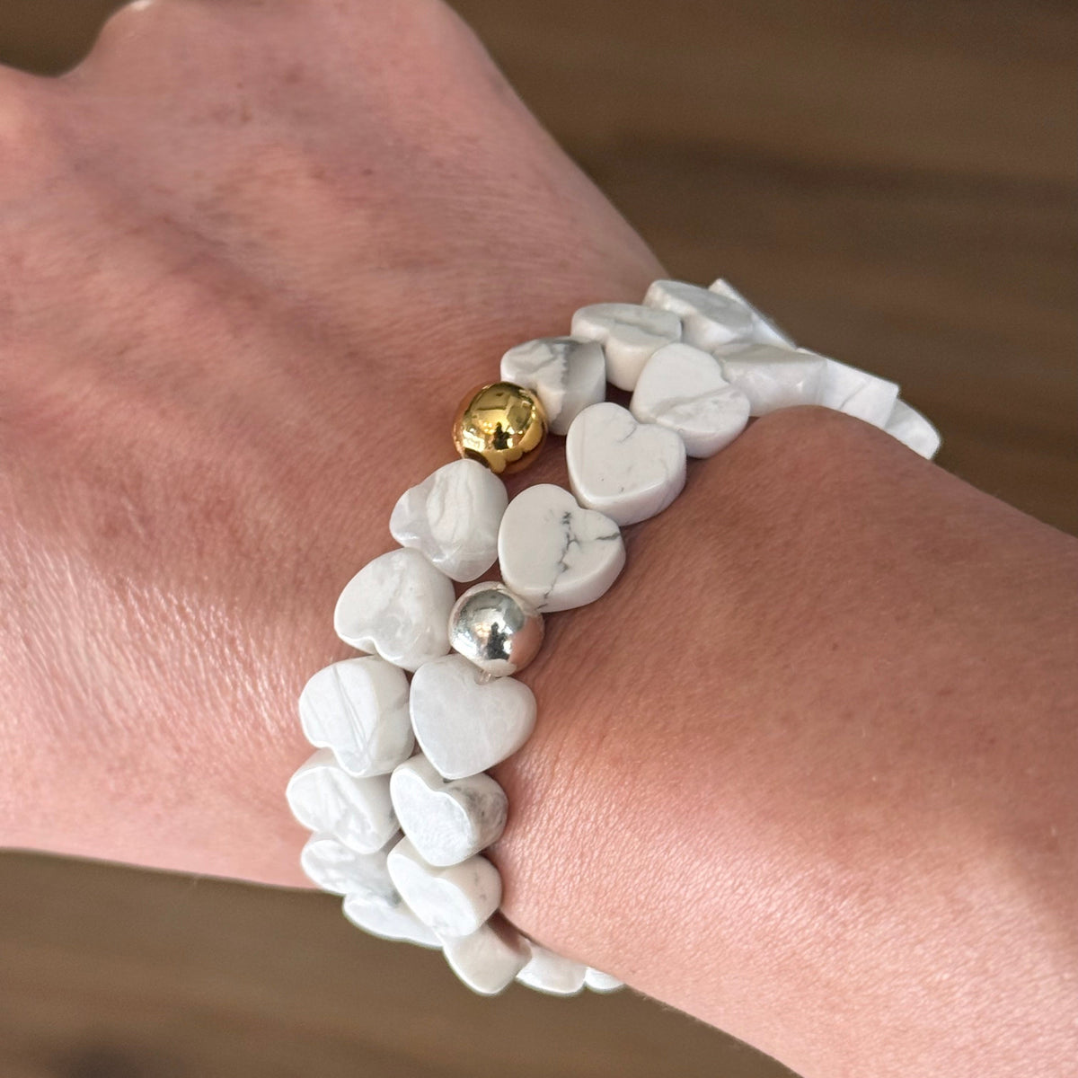 Howlite Heart Stretch-to-Fit Bracelets stacked on womans write - one with a gold accent bead and one with a silver accent bead