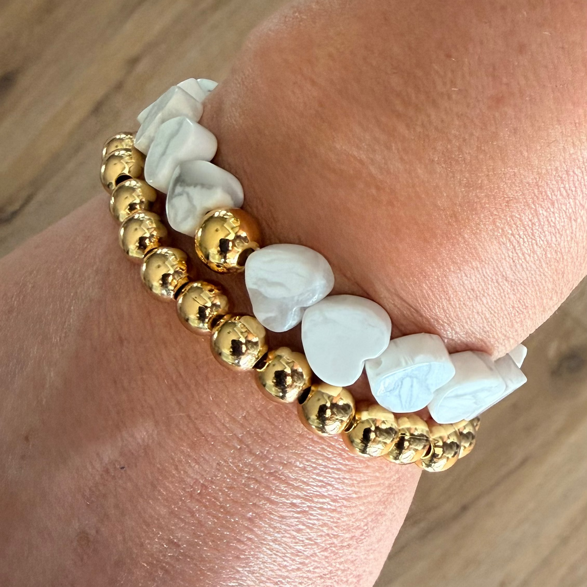 Howlite Heart Stretch-to-Fit Bracelet with one gold accent bead  paired with a gold beaded bracelet on womans wrist