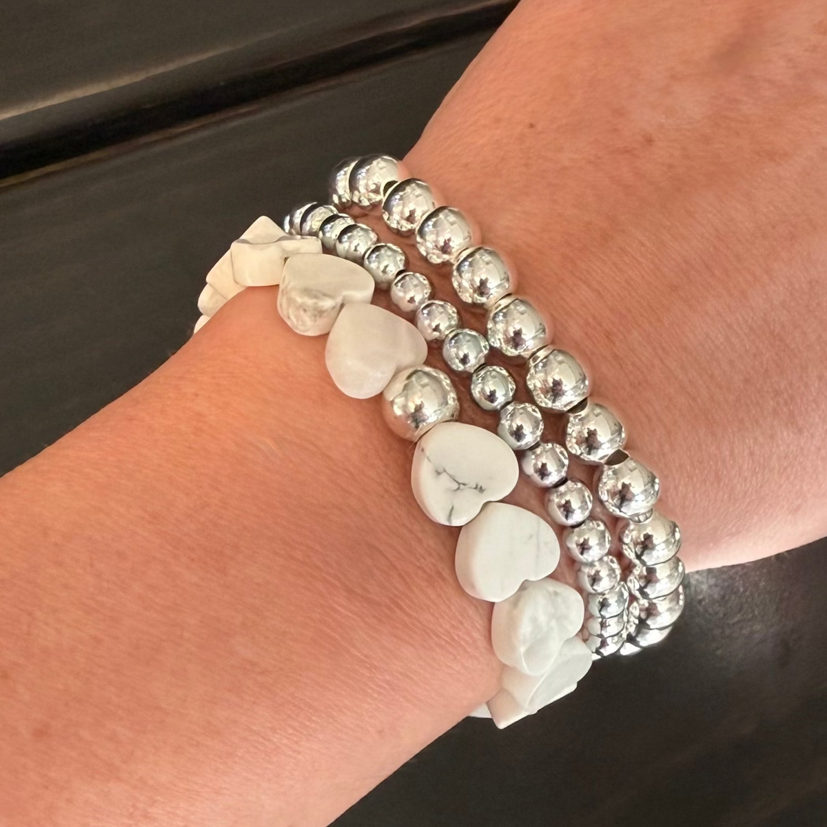 Howlite Heart Stretch-to-Fit Bracelet with one silver accent bead paired with two silver beaded bracelets on womans wrist