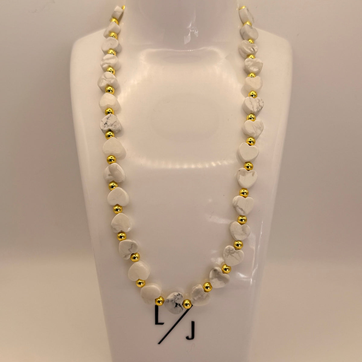 Howlite heart gemstone bead and gold filled bead necklace on stand