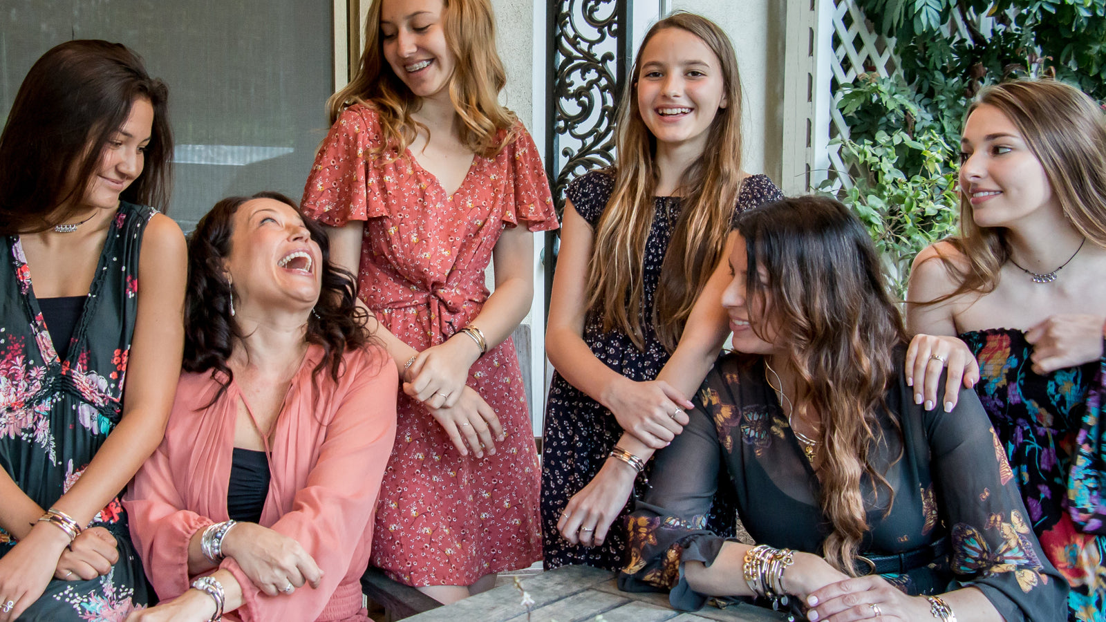 Group of women sitting together outdoors, smiling and enjoying each other's company.