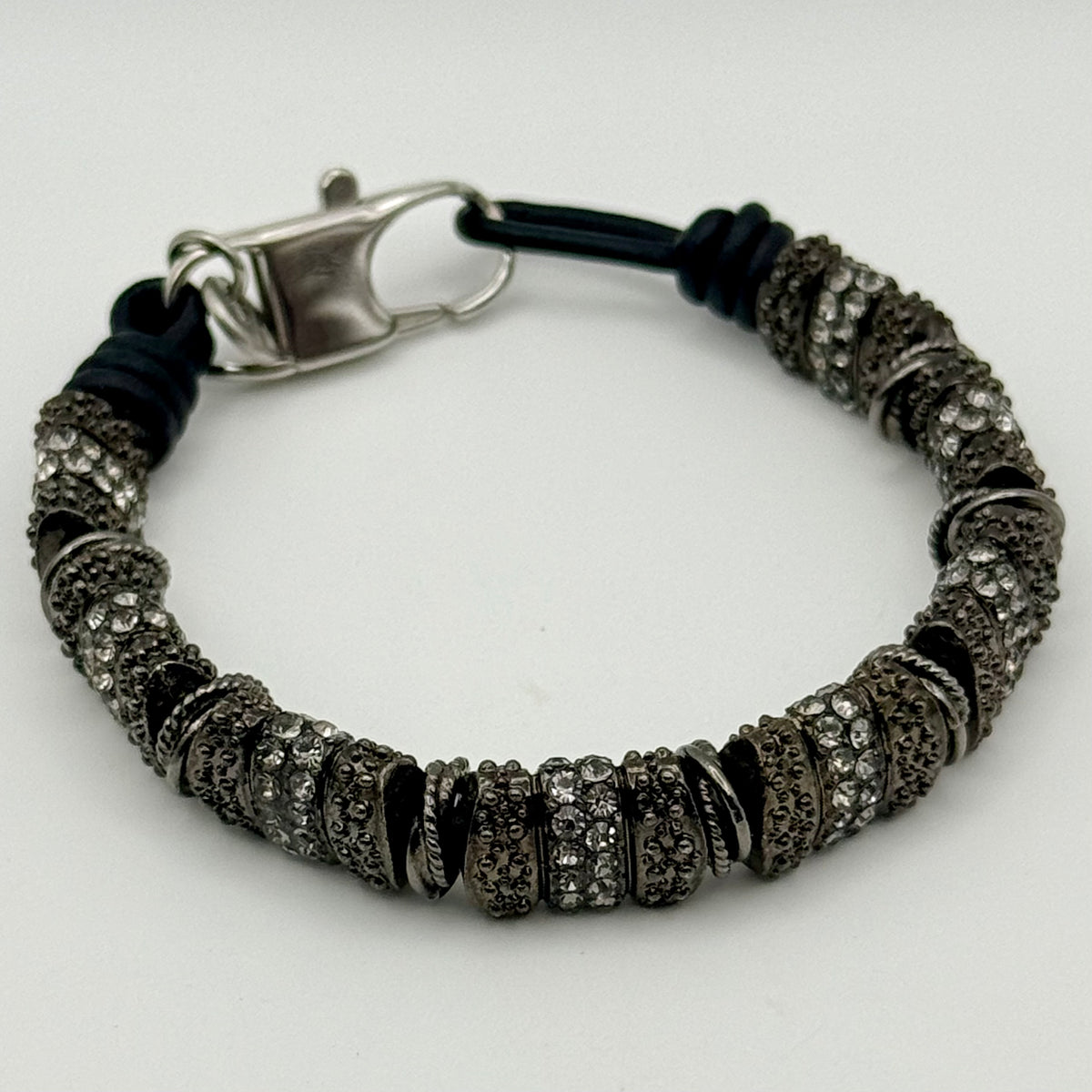 Bracelet with black cord and silver metal clasp on a white background