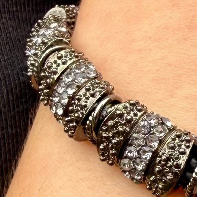 Close-up of a silver bracelet with intricate design on a wrist.
