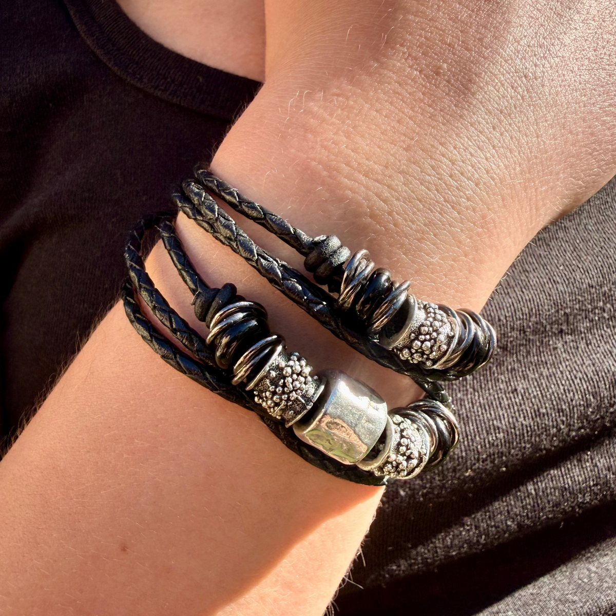 Close-up of a wrist wearing multiple leather bracelets with metal beads.