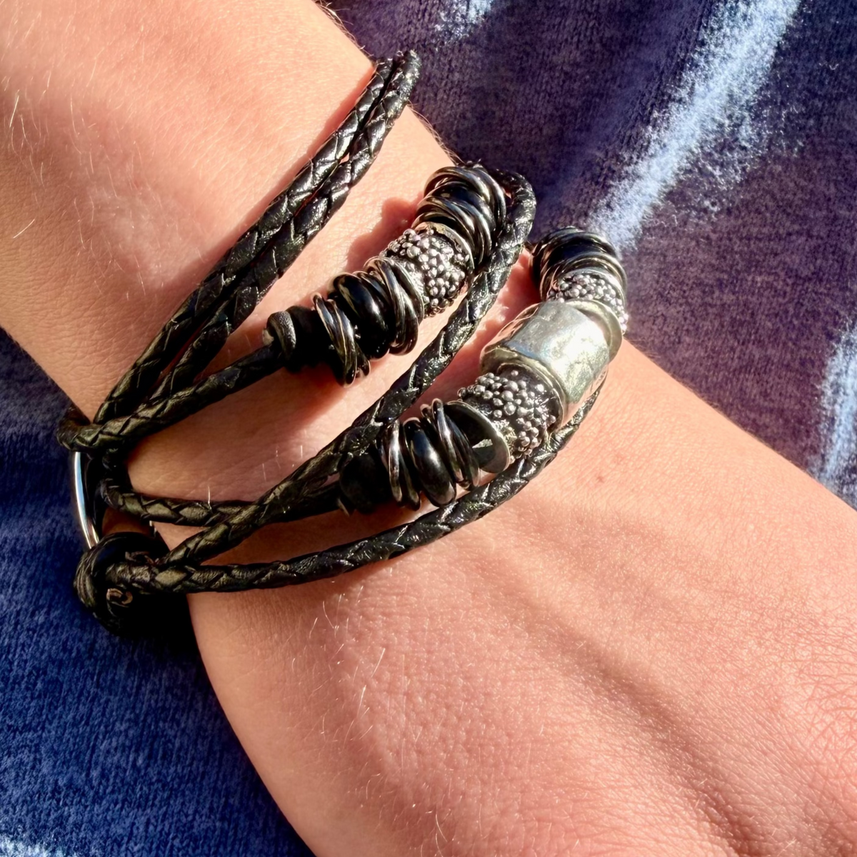 Close-up of a hand wearing multiple bracelets on a blue fabric background