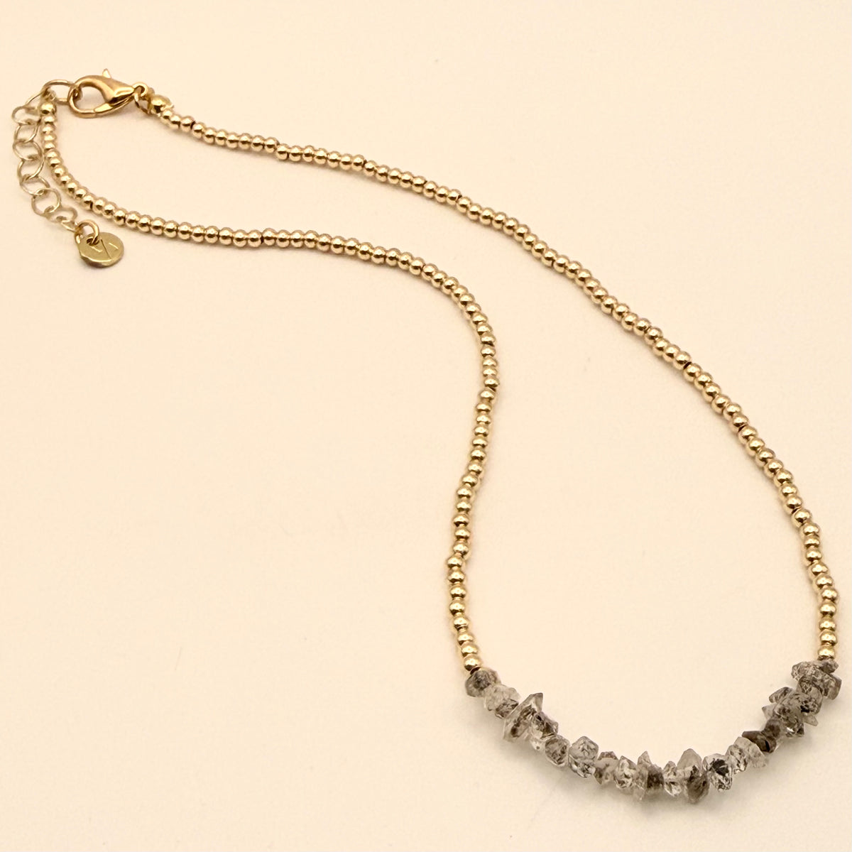 Gold chain necklace with gray gemstones on a beige background