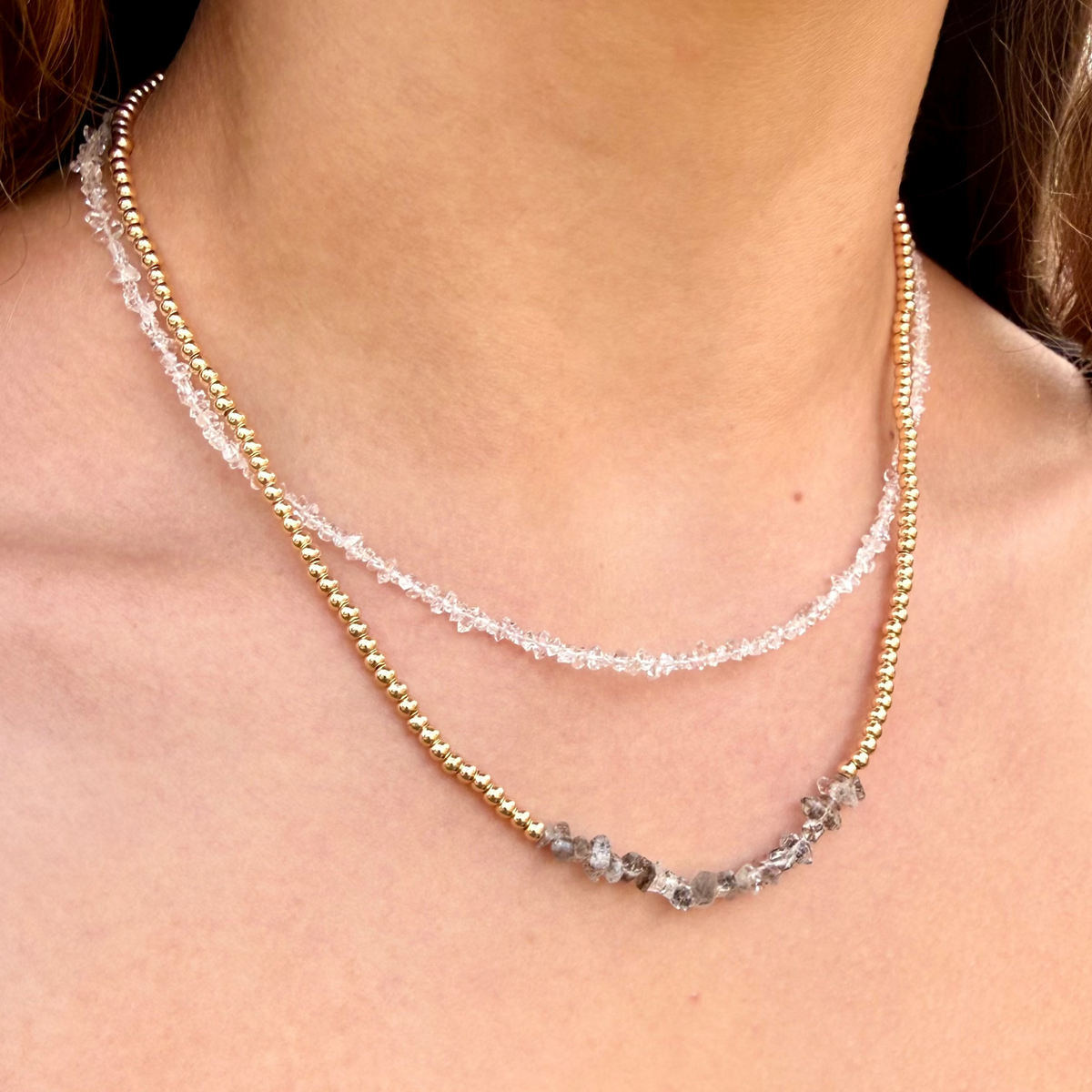 Close-up of a person wearing a delicate beaded necklace with a blurred background