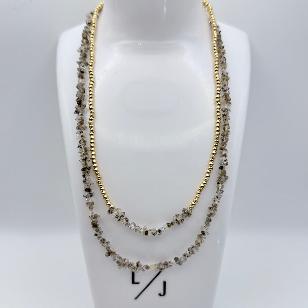 Two necklaces on a mannequin bust with 'LJ' branding.
