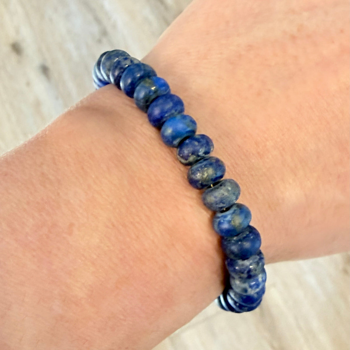 Blue beaded bracelet on a wrist with a light wooden background