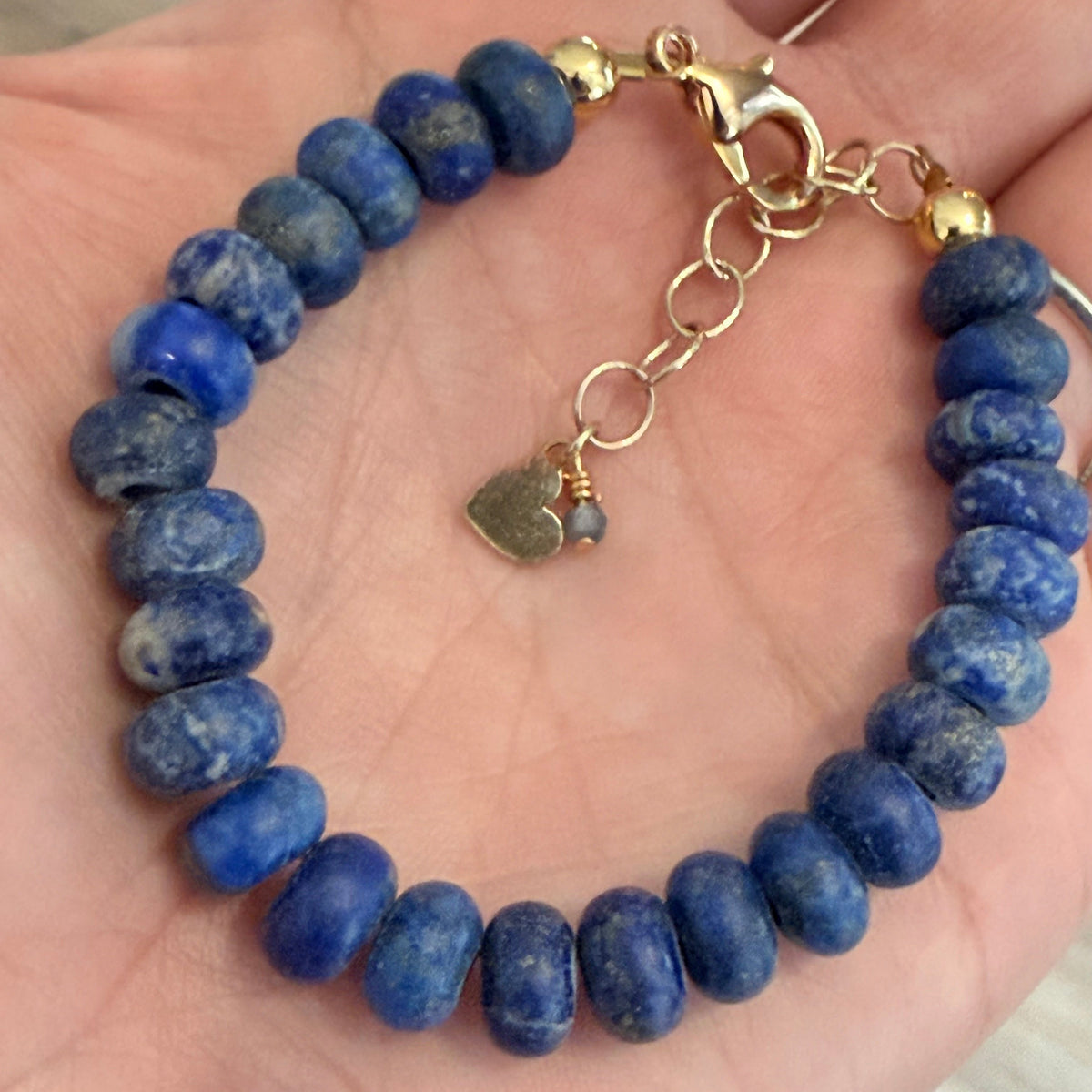 Blue beaded bracelet with gold clasp on a hand