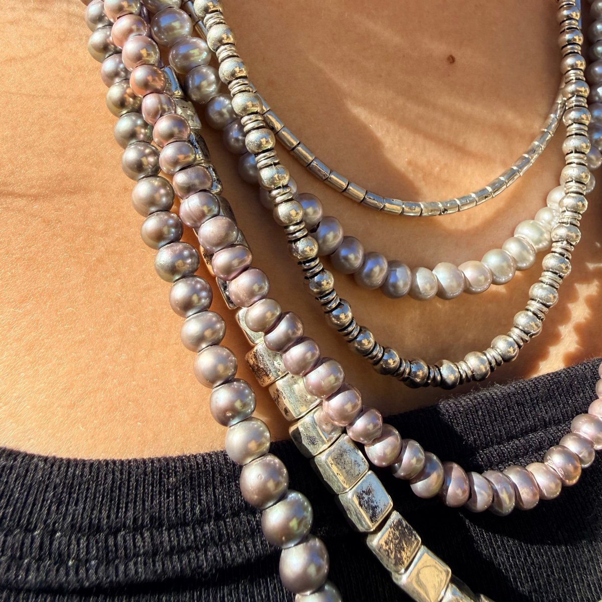 Close-up of a person wearing multiple pearl necklaces with a blurred background