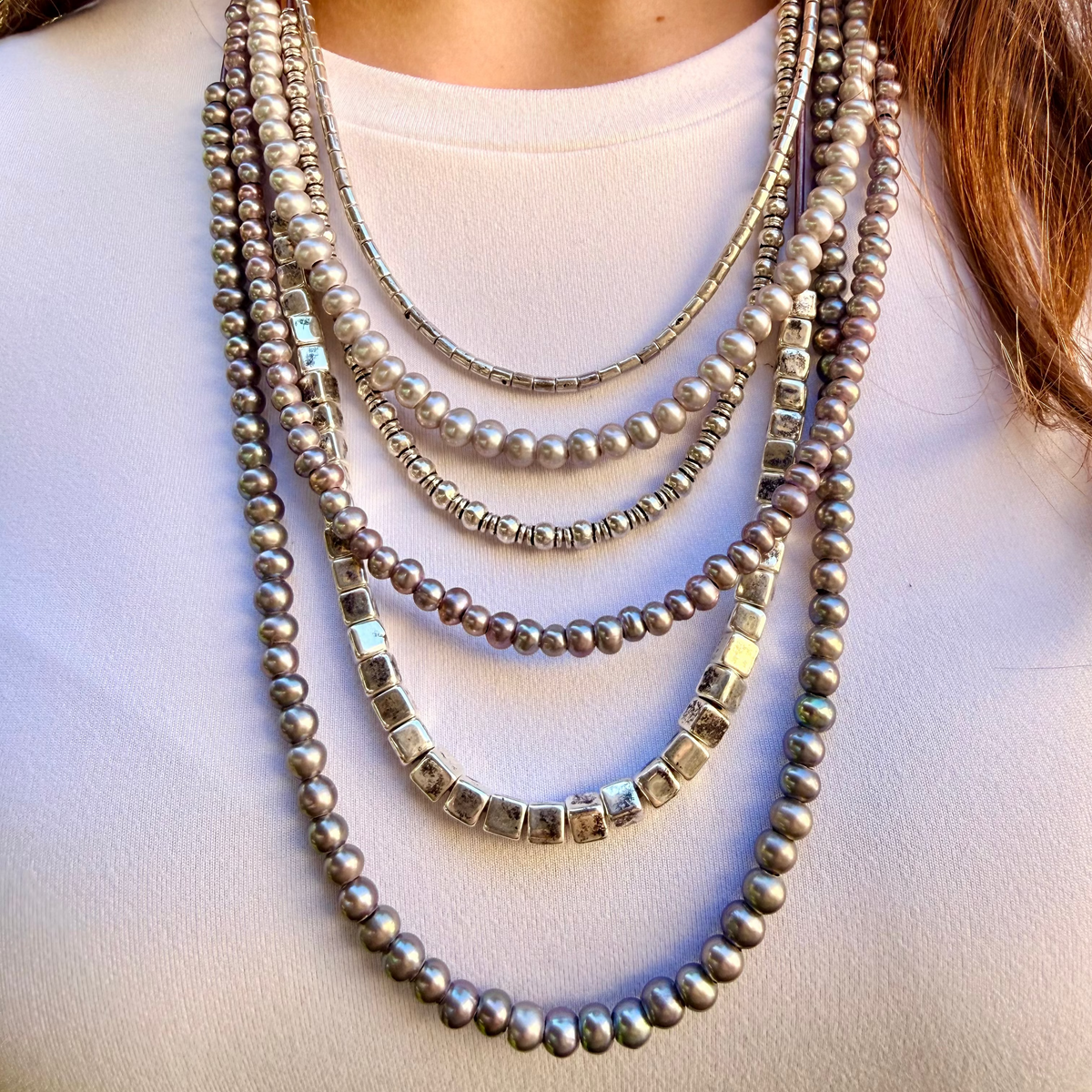 Multiple necklaces with beads and pearls on a white background