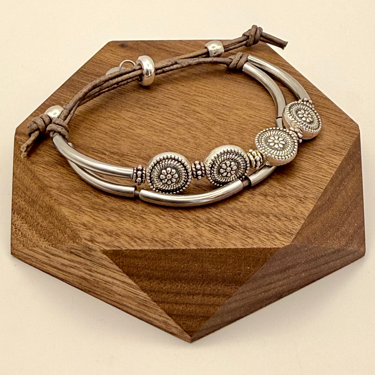 Bracelet with metal beads on a wooden stand against a beige background