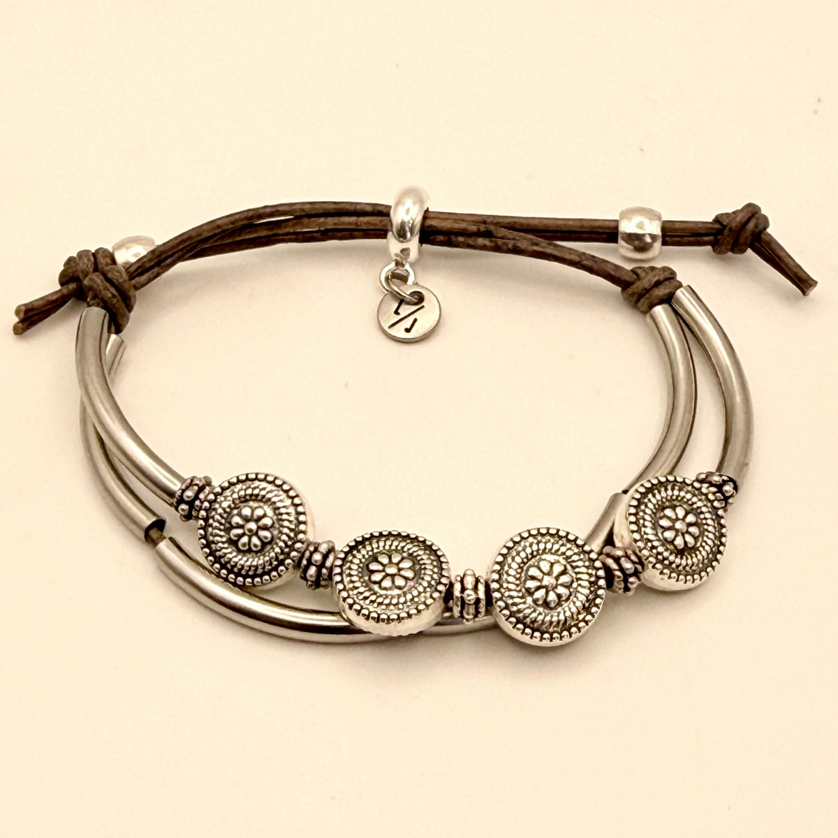 Silver bracelet with circular designs on a beige background