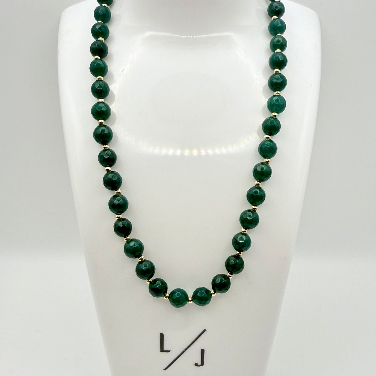 Dark emerald green jade large round beaded necklace with tiny gold bead accents on display