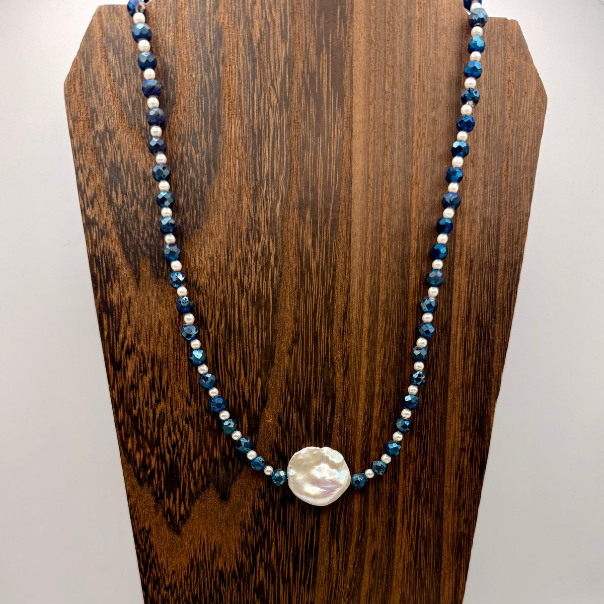 Necklace with blue and white beads on a wooden stand