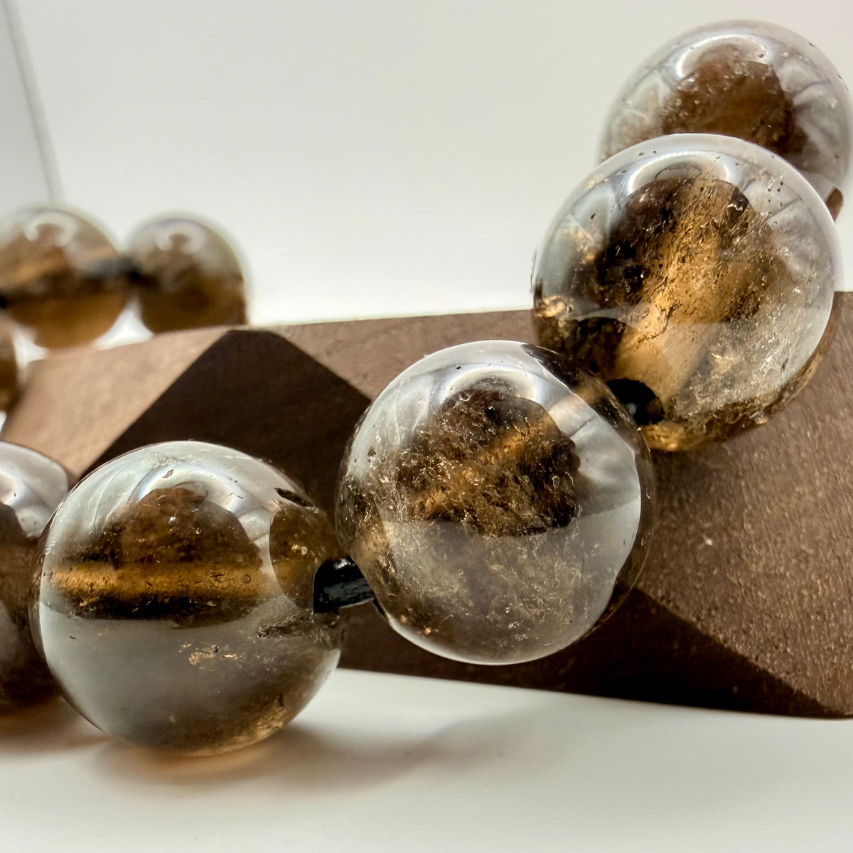 Close-up of clear and brown glass beads on a wooden block with a white background