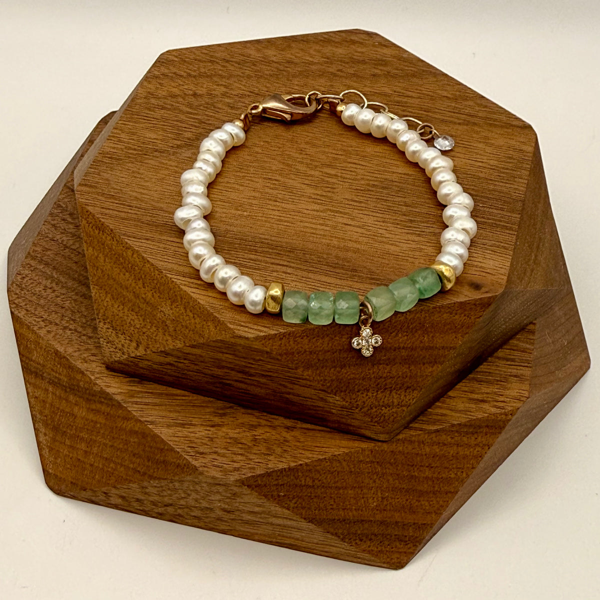 Pearl and green gemstone bracelet on a wooden stand