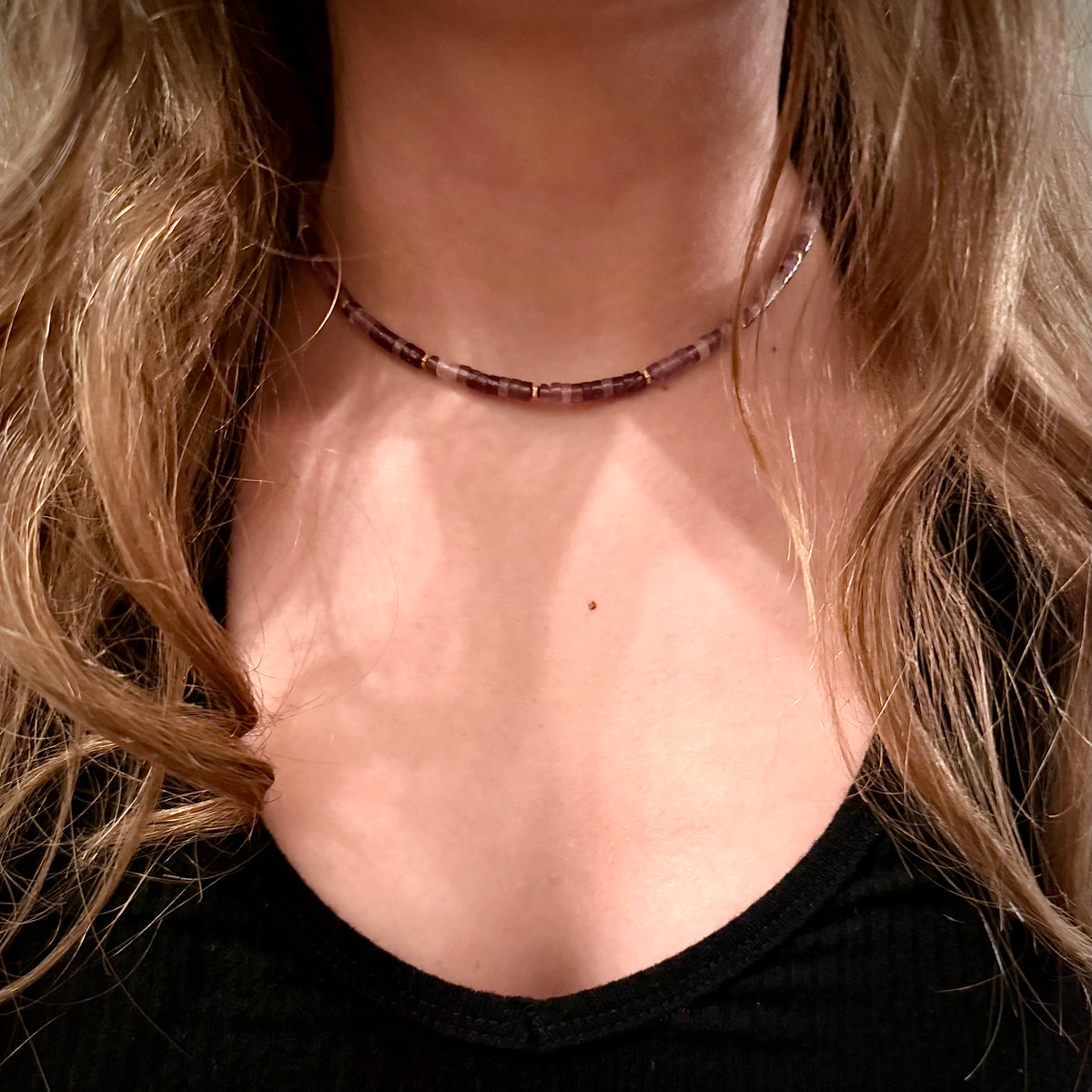 Close-up of a person wearing a beaded necklace with blonde hair.