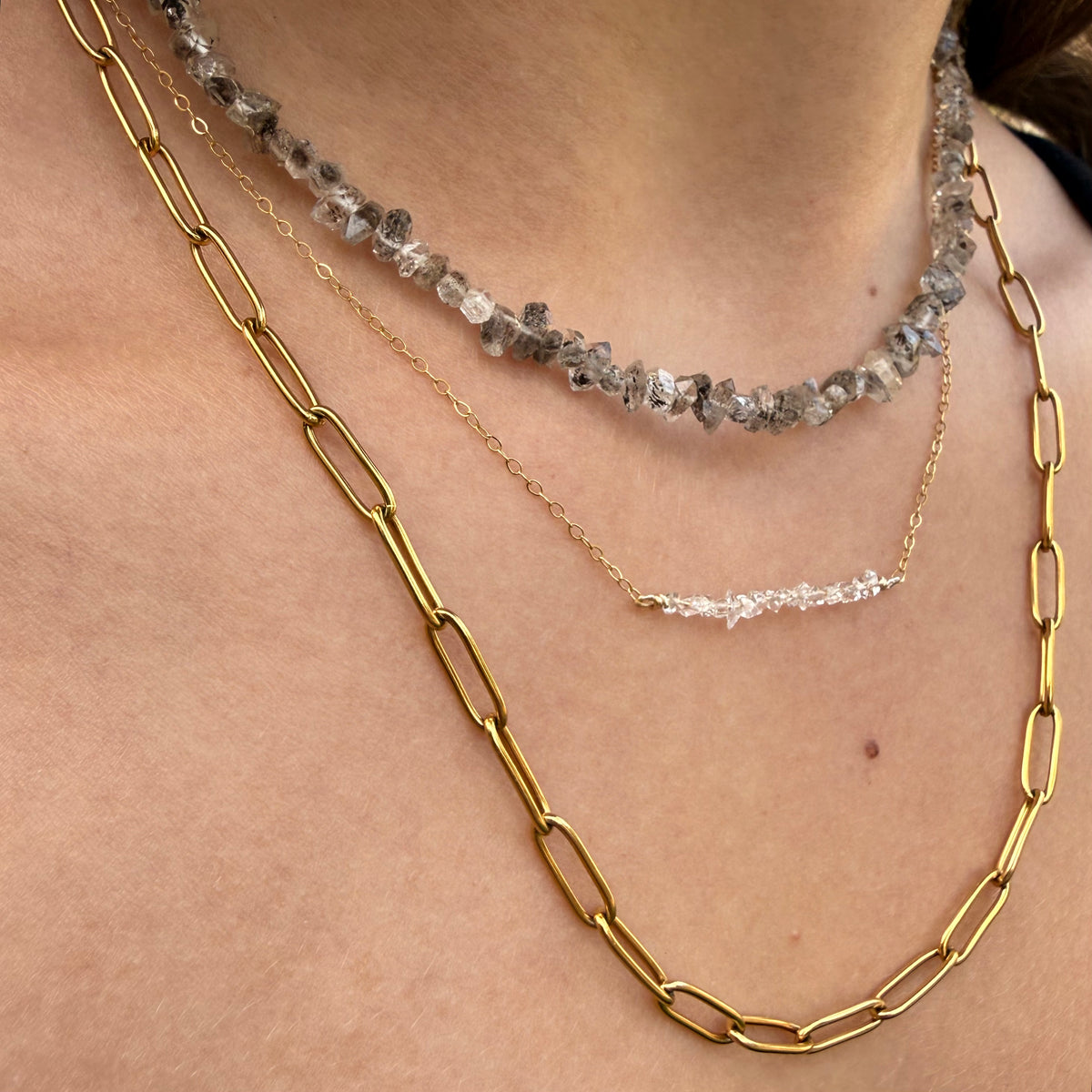 Close-up of layered necklaces on a person's neck
