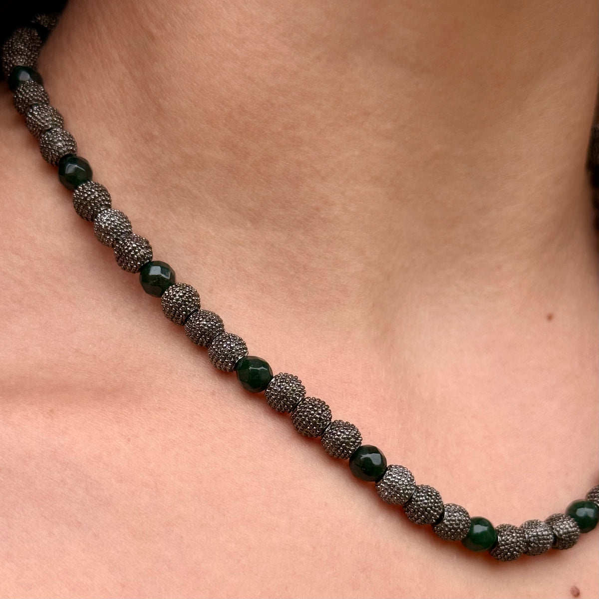 Close-up of Noa emerald green jade necklace with faceted jade beads and textured gunmetal accents